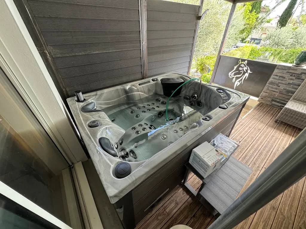 Spa installé sur une terrasse en bois abritée